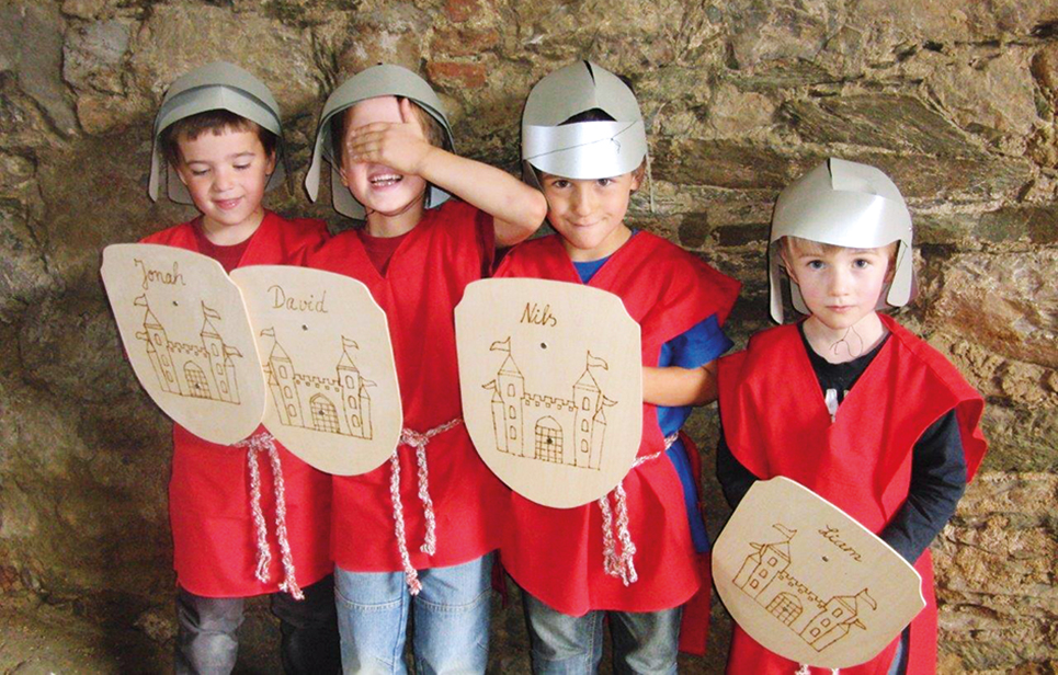 Vier Kinder mit selbst gebastelten Ritterhelmen und Schildern