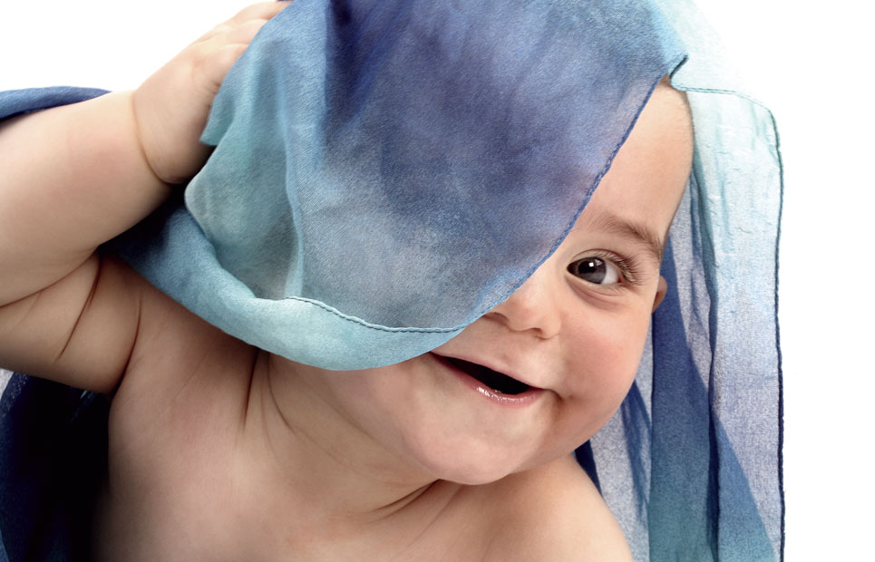 Baby lugt unter einem blauen Tuch hervor