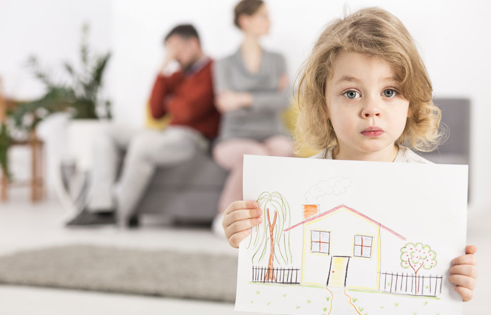 Kind hält traurig ein gemaltes Haus in der Hand, im Hintergrund sind die zerstrittenen Eltern zu sehen