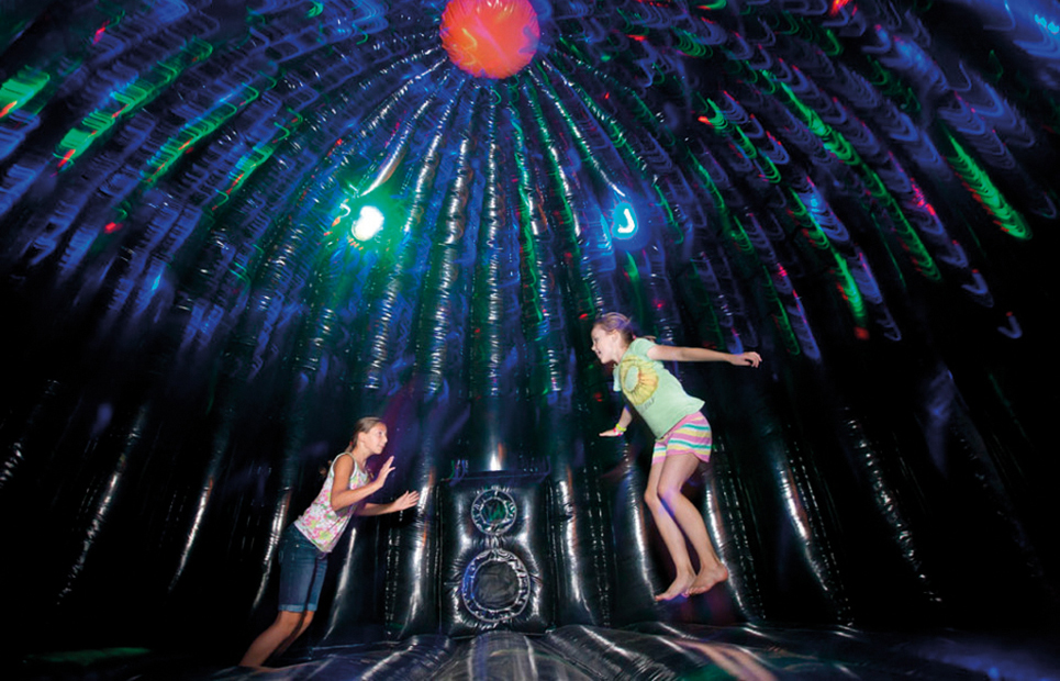 Kinder hüpfen in einer Discohüpfburg mit Licht und Musikanlage