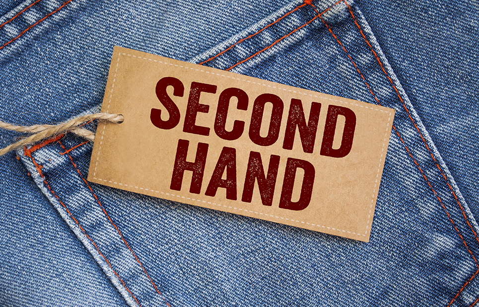 Ein Schild mit der Aufschrift "second hand" liegt auf einer Jeans