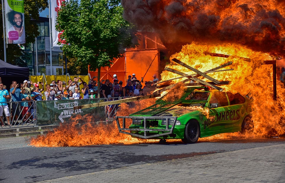 Ein Auto fährt durch eine brennende Holzwand