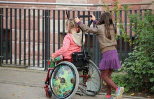 Ein Mädchen im Rollstuhl wird von einem anderen Mädchen geschoben