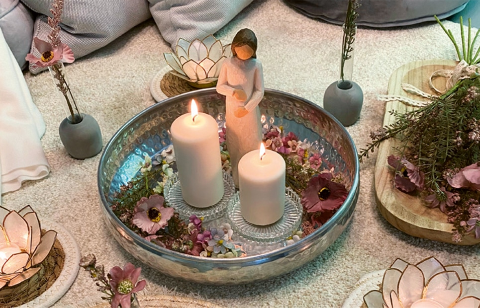 Man sieht ein silbernes Tablett mit Kerzen und Blüten um die Mutter zu ehren